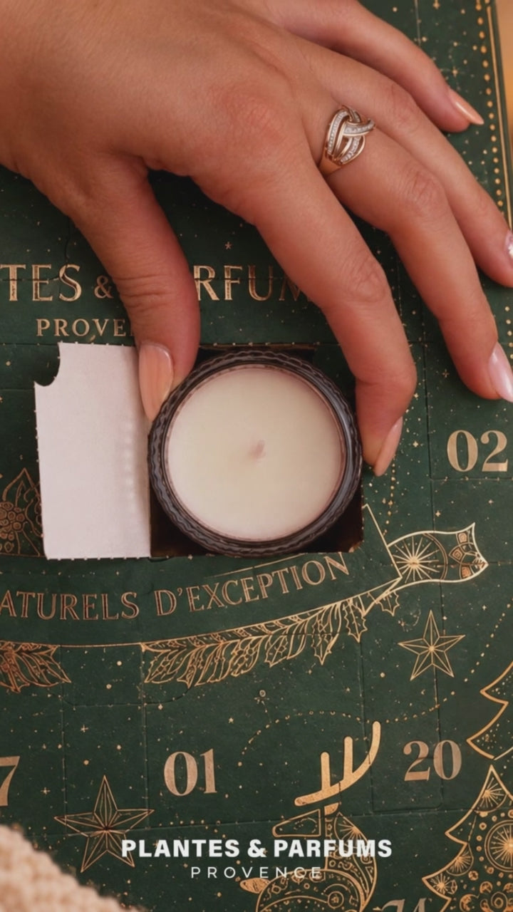 Main sortant une bougie parfumée en verre d'une case du calendrier de l'Avent